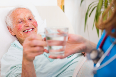 caregiver giving a glass of water for elder woman